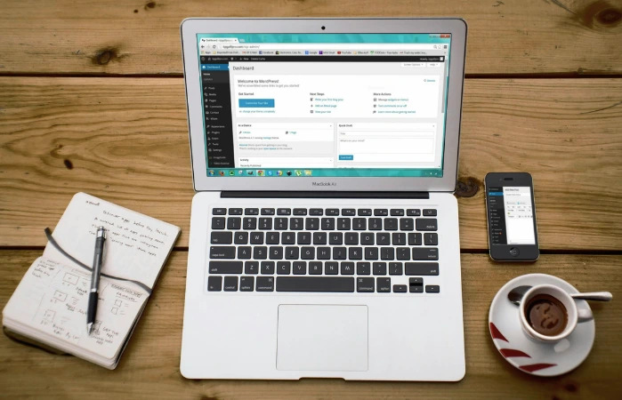 Bureau avec ordinateur MacBook, téléphone et café.