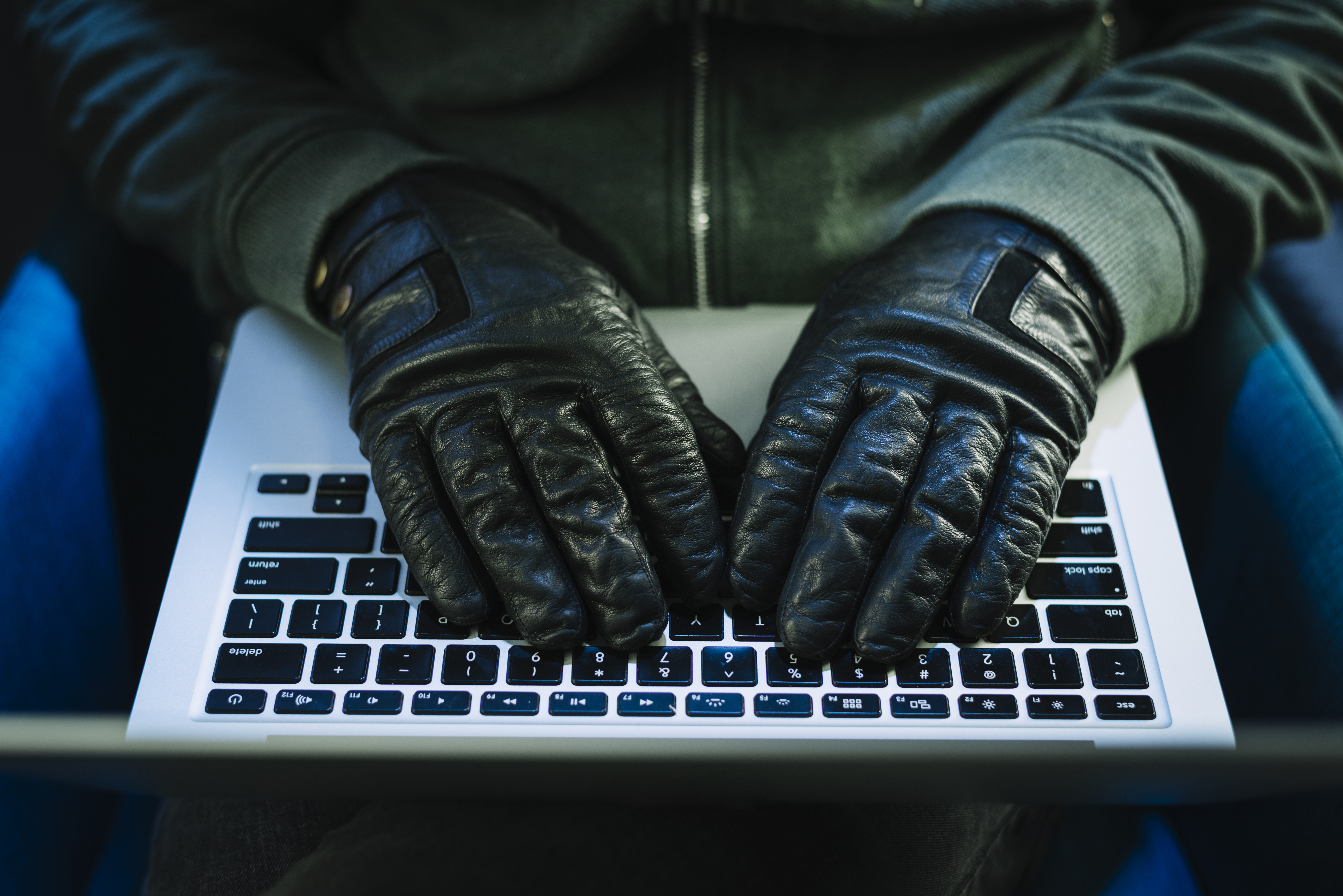 Mains en gants noirs tapant sur un clavier d'ordinateur