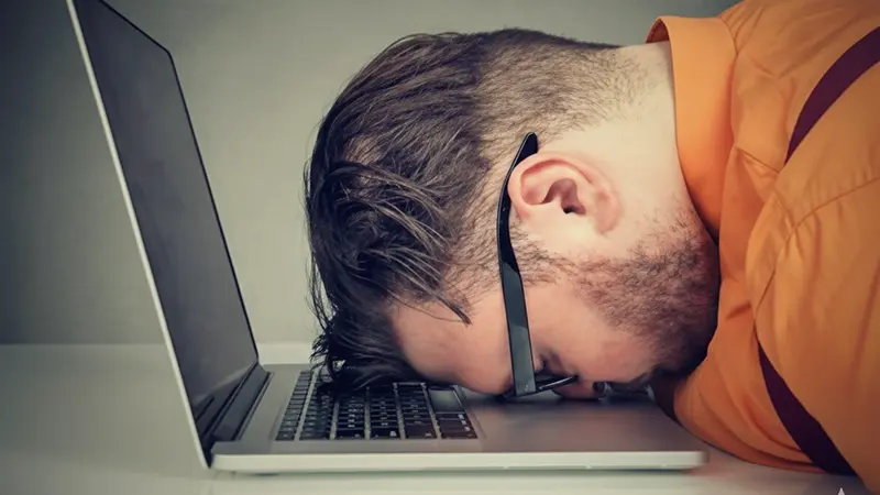 Exhausted man sleeping on his laptop