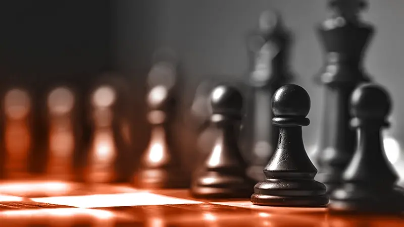 Chess pieces on a board, dramatic lighting.