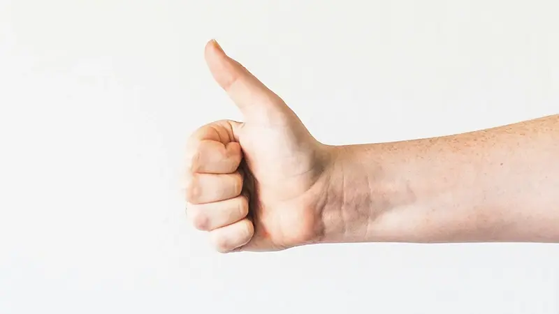 A hand giving a thumbs-up against a white background.