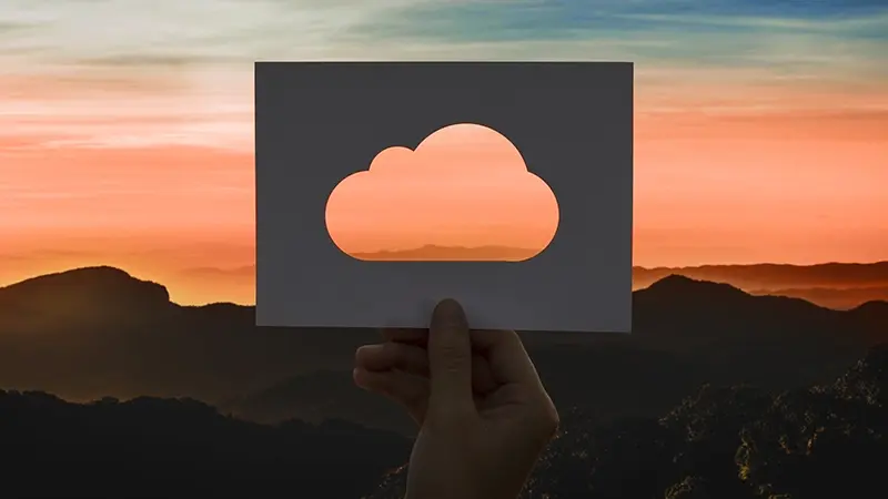 Holding a cloud-shaped cutout against a sunset