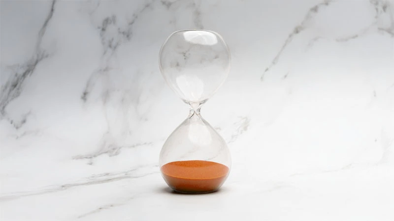 Sablier avec du sable orange sur marbre