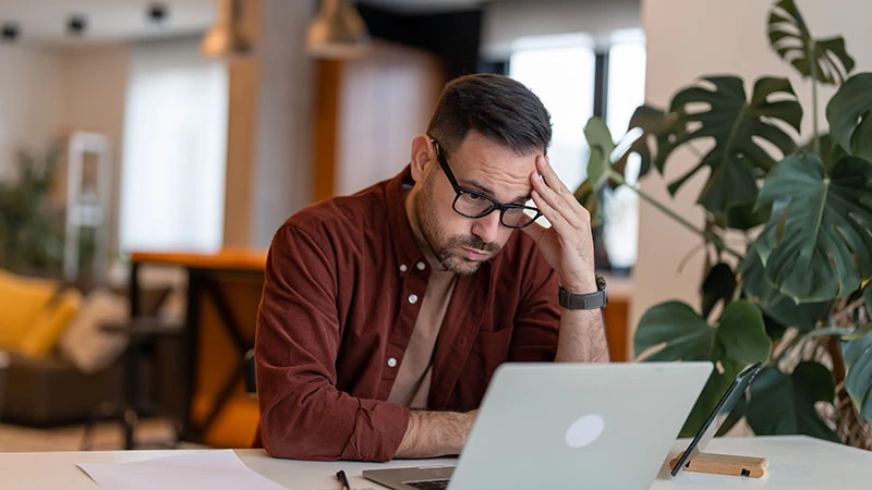 Homme inquiet travaillant sur ordinateur portable au bureau