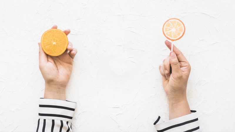 Holding an orange and an orange lollipop