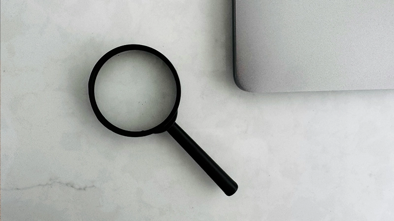 Magnifying glass and laptop on marble