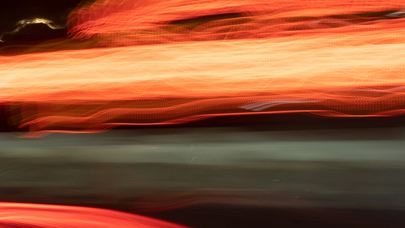 Orange and red light trails on a dark urban background