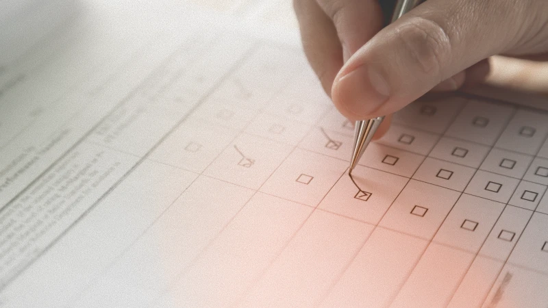 Une liste de contrôle avec des cases, certaines déjà cochées, tandis qu’une main tenant un stylo coche les autres.